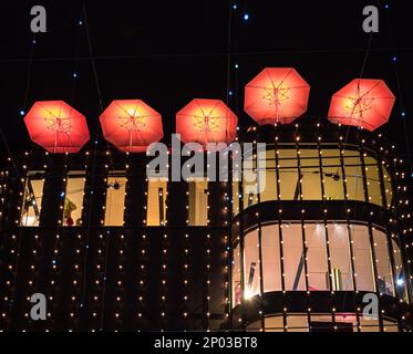 Zürich, Schweiz - 30. Dezember 2021: Rote Regenschirme auf dem Dach des Gebäudes in Zürich, rot beleuchtet bei Nacht Stockfoto