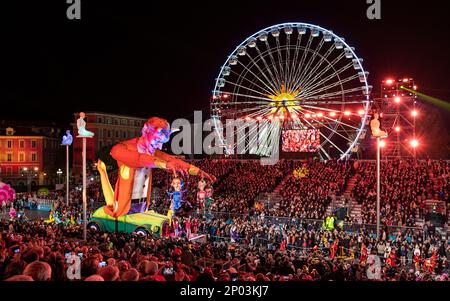 Lassen Sie sich bei Nacht (Teufelsmeisterpuppe) bei der jährlichen Lichterparade 150. in Nizza treiben. Großes Riesenrad im Hintergrund. Stockfoto