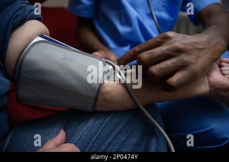 Eine afroamerikanische Krankenschwester misst den Blutdruck eines älteren Patienten Stockfoto
