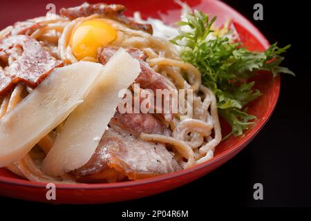 Pasta mit Käse, Speck und Spiegelei auf einem Teller, Nahaufnahme Stockfoto