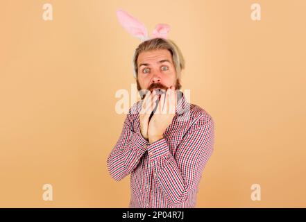 Frohen Ostertag. Hasenmann in Kaninchenohren. Ein überraschter bärtiger Typ mit Hasenohren. Kaninchenmann an Ostern. Verkauf. Rabatt. Ostereinkäufe. Frühling Stockfoto