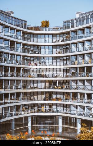 Ein vertikales Bild der modernen Fassade eines verglasten Gebäudes strahlt Wohlstand aus und die Reihe der Balkone mit nahtlosen Geländern schafft einen Intri Stockfoto
