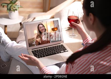 Frau mit einem Glas Wein hat online Party über Laptop zu Hause während Quarantäne-Abriegelung, Schließung Stockfoto