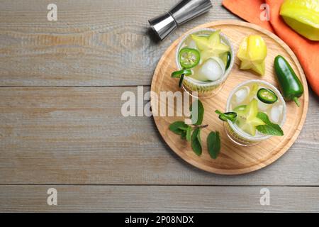 Gläser scharfer Cocktails mit Jalapeno, Karambola und Minze auf einem Holztisch, flach liegend. Platz für Text Stockfoto