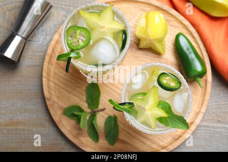 Gläser scharfer Cocktails mit Jalapeno, Karambola und Minze auf einem Holztisch, flach liegend Stockfoto