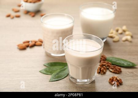 Verschiedene vegane Milch und Nüsse auf Holztisch, Nahaufnahme Stockfoto