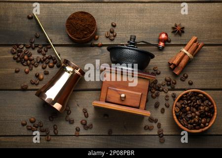 Manuelles Kaffeepulver aus Vintage, Bohnen, Pulver, Zimt und Jezve auf Holztisch, flach liegend Stockfoto