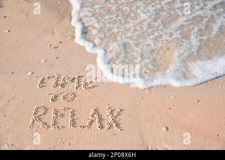 Zeit zum Entspannen am Strand auf Sand geschrieben Stockfoto