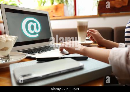 Eine Frau, die E-Mails per Laptop im Café verschickt Stockfoto