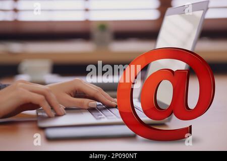 Am Schild und Frau, die am Tisch eine E-Mail per Laptop verschickt, Nahaufnahme Stockfoto