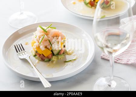 Ein Krabbensalat serviert mit Weißwein und Licht von hinten. Stockfoto