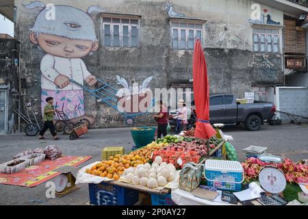 Ein Wandgemälde des Künstlers Alex Face auf dem nassen Markt von Phuket Town, Thailand, mit seiner dreiäugigen Markenfigur Mardi, die als Marktportier arbeitet Stockfoto