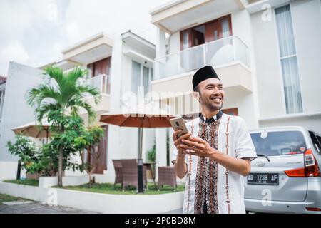 Asiatischer muslimischer Mann mit Songkok mit Smartphone Stockfoto