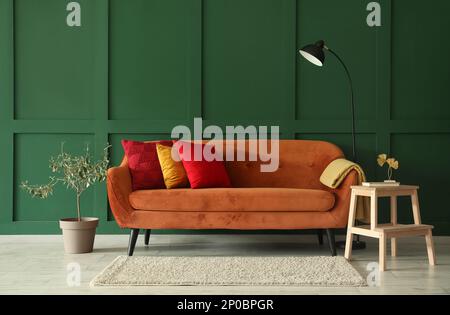 Stilvolles Wohnzimmer mit rotem Sofa, Trittleiter und Lampe Stockfoto