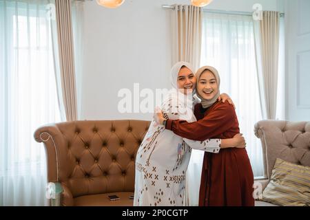 Zwei lächelnde muslimische Frauen, die sich umarmen Stockfoto