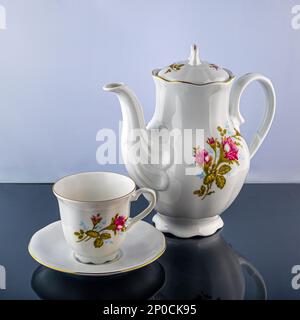 Porzellangeschirr, Kaffee- oder Teetasse. Tee- oder Kaffeekanne und Zuckerdose. Handbemalte Blumen. Kann zur Veranschaulichung von Porzellan in Zeitungen verwendet werden. Stockfoto