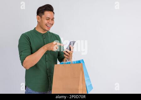 Ein glücklicher asiatischer Mann, der lächelt und auf seine Hand zeigt Stockfoto