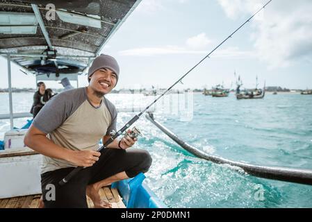 Nahaufnahme eines lächelnden Anglers, der beim Verlassen eine Angel hält Stockfoto