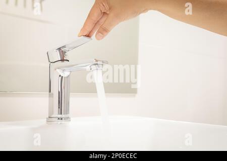 Schließen Frau öffnen Pull Chrom Wasserhahn Waschbecken zum Waschen Hand Seife für Corona Virus am Wasserhahn. Den fließenden Wassertropfen abdrücken. Badezimmer Stockfoto