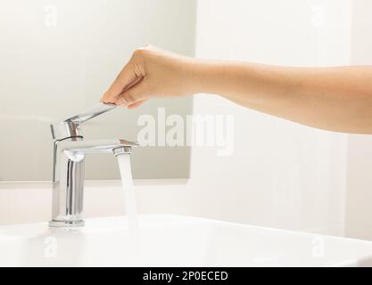 Schließen Frau öffnen Pull Chrom Wasserhahn Waschbecken zum Waschen Hand Seife für Corona Virus am Wasserhahn. Den fließenden Wassertropfen abdrücken. Badezimmer Stockfoto