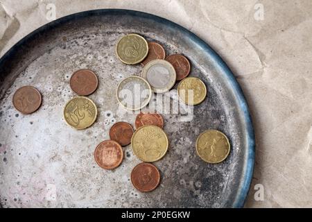 Einige Euro-Münzen auf einem Teller in der Nähe verstreut. Verschiedene Geld der Europäischen Union von oben Stockfoto