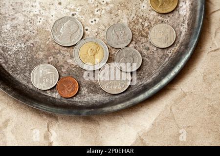 Einige thailändische Münzen auf einem Teller in der Nähe verstreut. Verschiedene Geld von Thailand mit dem König profile Top View Stockfoto