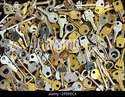 Viele verschiedene gelbe und weiße alte Metallschlüssel haben die Wahl, eine Tür zu öffnen. Vintage Nahaufnahme Hintergrund Stockfoto