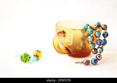 Original bunte Murano Glasperlen und Bonbons. Traditionelle venezianische Millefiori Halskette in eine Kaffeetasse. Reihe von blauen Perlen Stockfoto