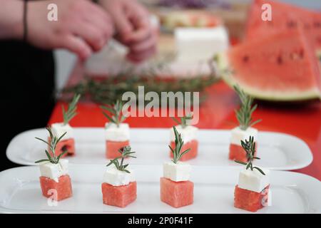 Zubereitung von Wassermelonen- und Fetakäsewürfeln mit Rosmarin. Authentische griechische Küche mit selektivem Fokus Stockfoto