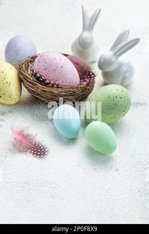 Ostern-Hintergrund. Ostereier im Nest mit Dekor. Frohes Osterkonzept. Eier und Kaninchen auf Betonhintergrund Stockfoto