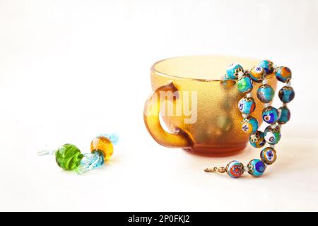 Original bunte Murano Glasperlen und Bonbons. Traditionelle venezianische Millefiori Halskette in eine Kaffeetasse. Reihe von blauen Perlen Stockfoto