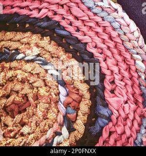Close-up Runde handgefertigtes Teppich Hintergrund. Gestrickte Textil Teppich Muster Makro. Altes Tuch Recycling Vintage Matte Textur Stockfoto
