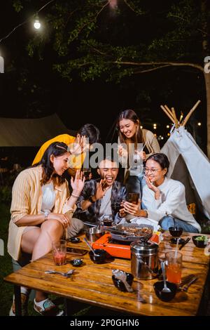 Eine Gruppe von Personen führt Videoanrufe mit jemandem am Telefon Stockfoto