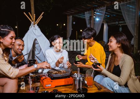 Eine Gruppe von Leuten hängen zusammen ab und grillen das Rindfleisch zufällig Stockfoto