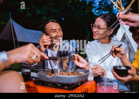 Ein Typ in einem karierten Hemd und eine Frau in einem weißen Strickpullover, die zusammen lachen Stockfoto