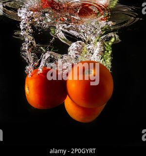 Reife Tomate fällt tief unter Wasser mit einem big Splash. Stockfoto