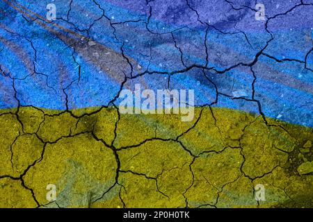 Ukrainische Flagge auf der gebrochenen Erde. Staatsflagge der Ukraine. Erdbeben- oder Dürrekonzept. Stockfoto