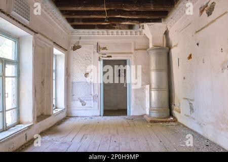 Blick auf ein verlassenes Bauwerk, das jetzt größtenteils ruiniert ist und auf die Restaurierung wartet. Ein schlichtes, weiß getünchtes Nebenzimmer. In einem alten, historischen, klassischen, traditionellen Stockfoto