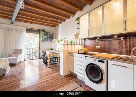 Geräumiges, modernes Wohnzimmer mit Küche und offenem Balkon mit modernen Geräten und Möbeln. Konzept im mediterranen Stil Stockfoto