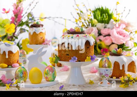 Festlicher Ostertisch. Osterkuchen, Ostereier, Blumenarrangements und Heimdekorationen für den Urlaub. Stockfoto