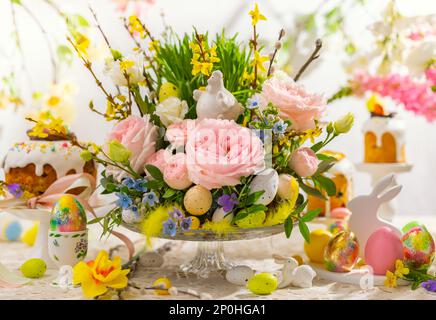 Stille Ostern mit Blumenkomposition und traditionellem Ostergeschenk auf festlichem Tisch mit Frühlingsblumen. Ostertisch. Stockfoto