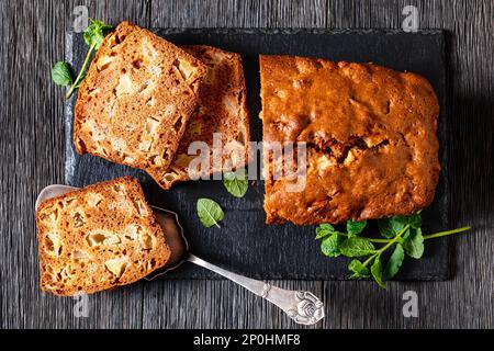 Apfelzimtbrot auf Schieferbrett auf dunklem Holztisch, horizontale Ansicht, Nahaufnahme Stockfoto