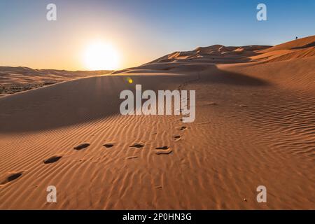 Fußabdrücke in den Sanddünen der Wüste Abu Dhabi bei Sonnenuntergang. Stockfoto