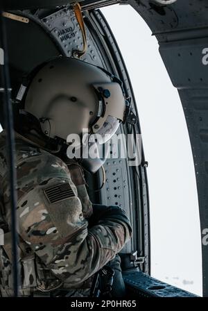 EIN US-AMERIKANISCHER Der dem 1.-211. Luftbataillon der Nationalgarde der Utah-Armee zugeteilte Chef der Armeemannschaft hält am Boden eine Sichtlinie aufrecht und ermöglicht gleichzeitig einen Luftwechsel mit Soldaten, die der 19. Spezialeinsatzgruppe (Airborne) am 21. Januar 2023 in der Nähe von Camp Williams, Utah, zugewiesen wurden. Der Besatzungschef ist für die gesamte Hubschraubercrew verantwortlich und gilt als verantwortlich für alles, was im oder am Hubschrauber passiert. (Utah Army National Guard Foto von SPC. Mackenzie Willden) Stockfoto