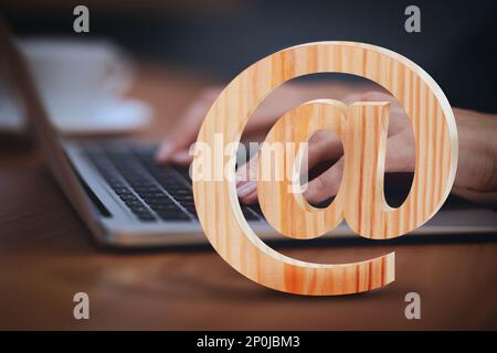 Am Schild und Frau, die am Tisch eine E-Mail per Laptop verschickt, Nahaufnahme Stockfoto