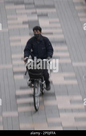 Ein Mann, der mit dem Fahrrad durch die Straßen in Japan fährt Stockfoto