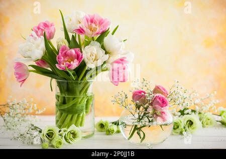 Wunderschöne Blumen in Vase auf dem Holztisch. Tulpen, Rosen und Eustoma. Stockfoto