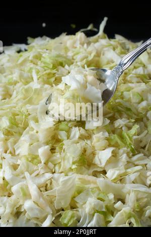 Ein Haufen gehackter Grünkohlblätter mit Silberlöffel, weiß und blassgrün, sehr nahrhaft und reich an Ballaststoffen, bereit zum Kochen Stockfoto