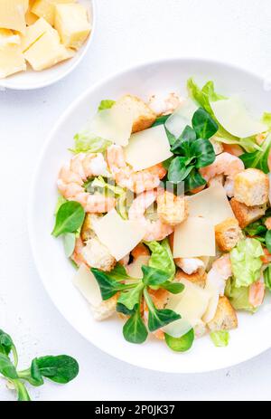 Caesar Salat mit Garnelen, Eisberg und Lammsalat, Croutons, Parmesan mit caesar Dressing. Weißer Tischhintergrund, Draufsicht Stockfoto