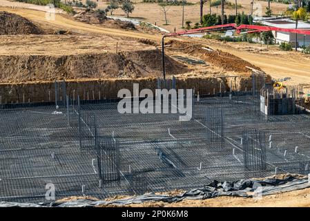 Betonpumpe, die auf einem verstärkten Fundament auf einer großen Baustelle arbeitet Stockfoto